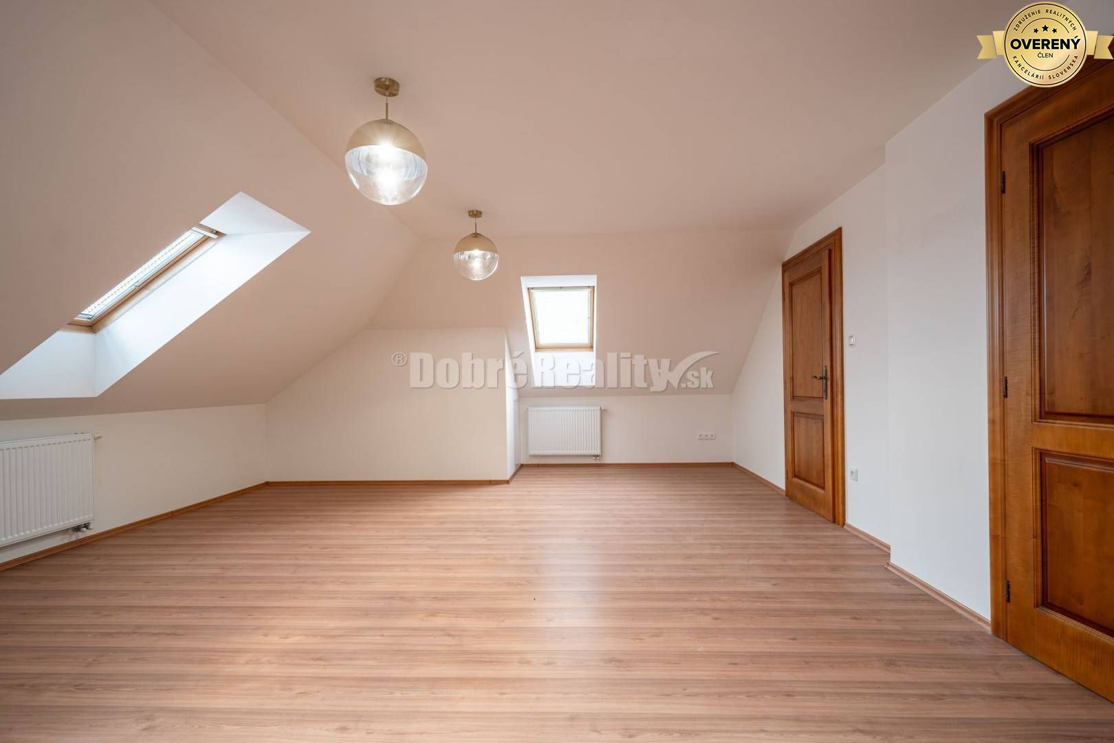 Podkrovná miestnosť s podlahou s dreveným dekorom a strešnými oknami v rodinnom dome.