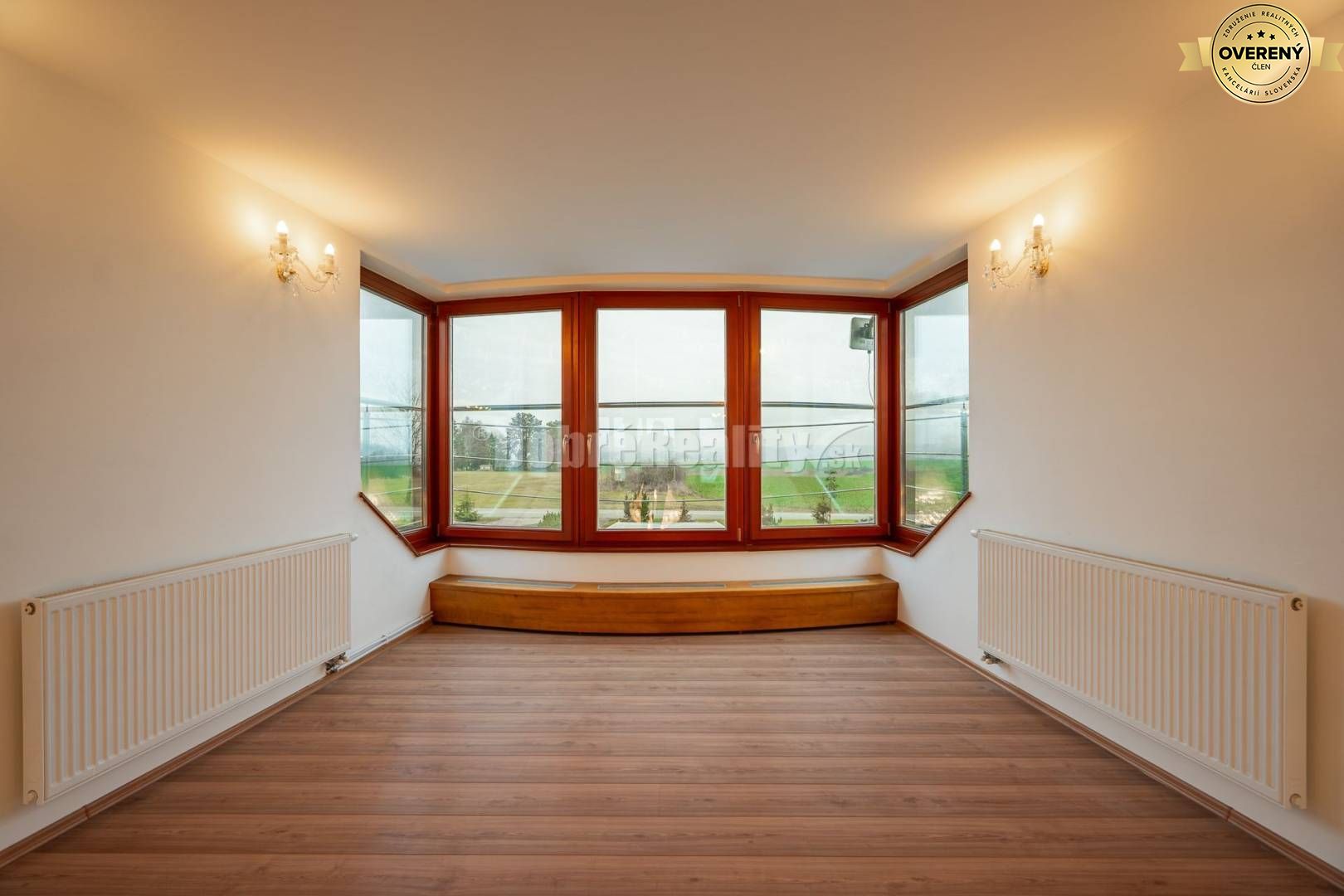 Izba v rodinnom dome s veľkým oknom a podlahou s dreveným dekorom.