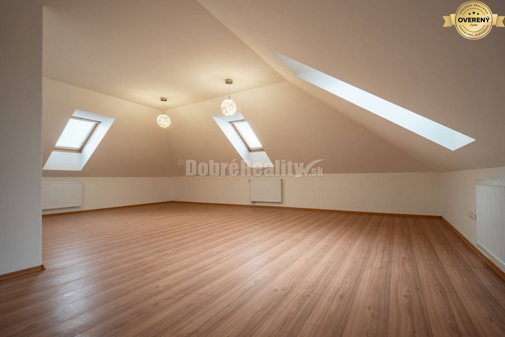 Podkrovná miestnosť s veľkými oknami a podlahou s dreveným dekorom v rodinnom dome.