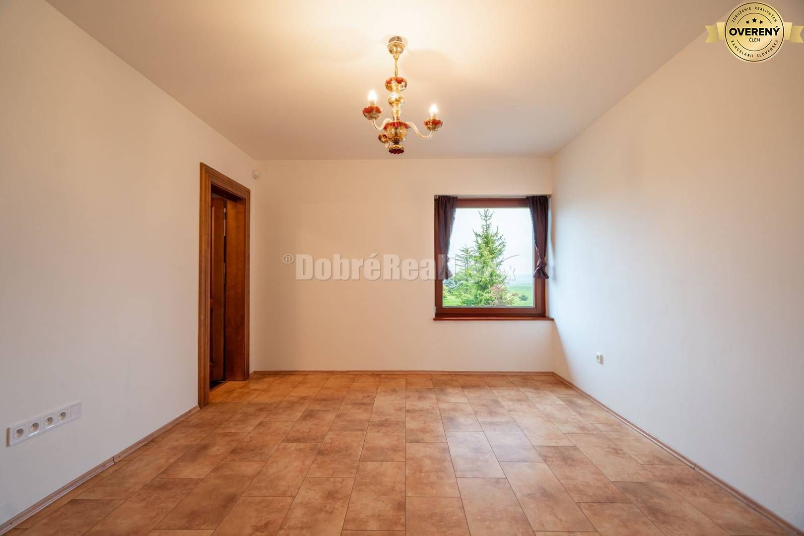 Miestnosť s oknom, lustrom a podlahou s dreveným dekorom v rodinnom dome.