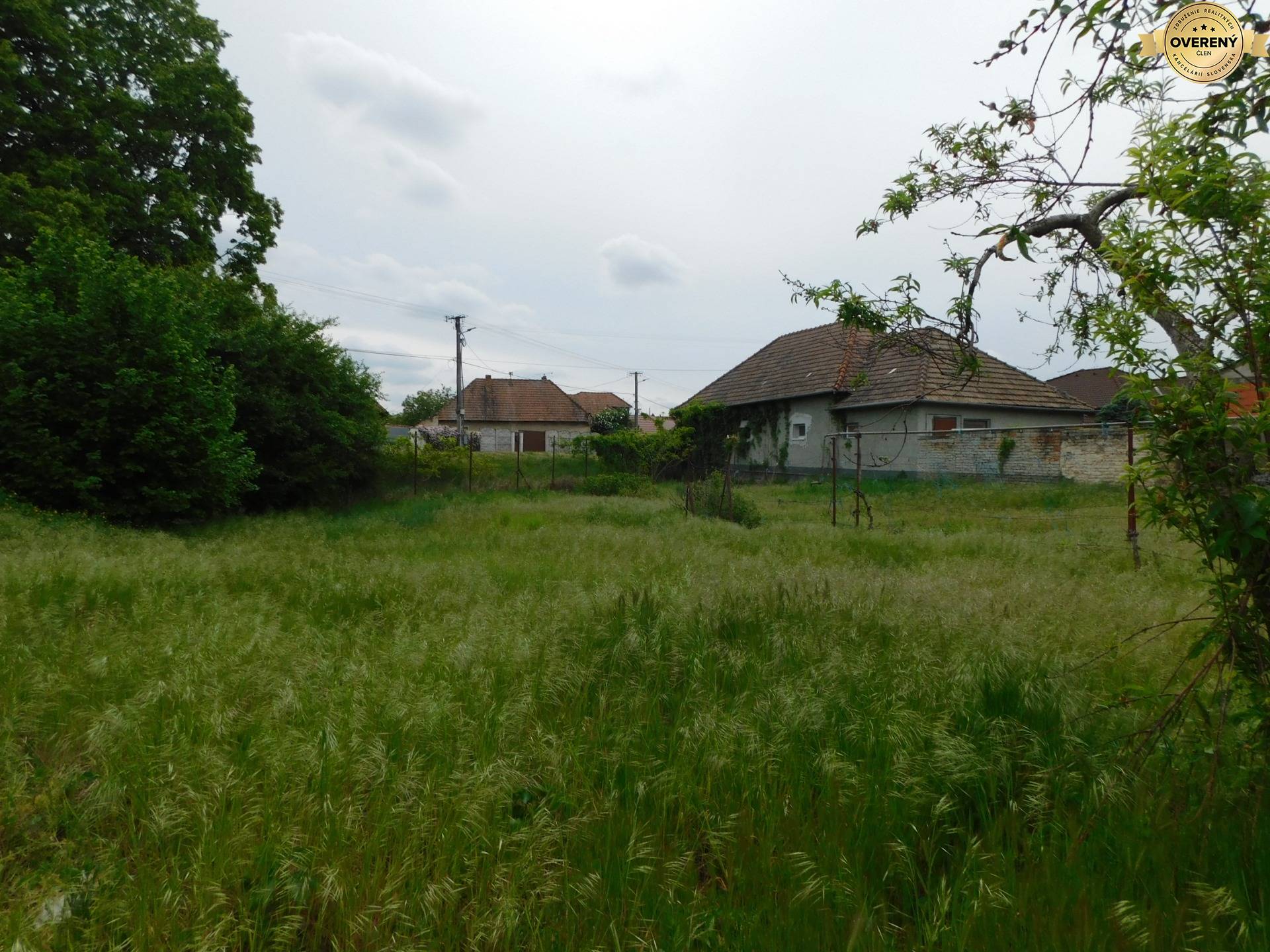 Pozemok na bývanie v Dvoroch nad Žitavou, obklopený zeleňou a vidieckymi domami.